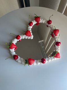 a heart shaped cake with strawberries on it sitting on a table next to a mirror