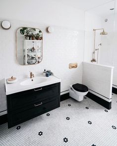 a bathroom with black and white flooring and tiled walls, along with a mirror on the wall