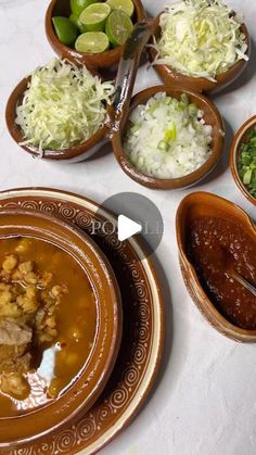 a table topped with bowls filled with different types of food next to plates and spoons