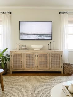 a living room filled with furniture and a painting hanging on the wall above it's windows