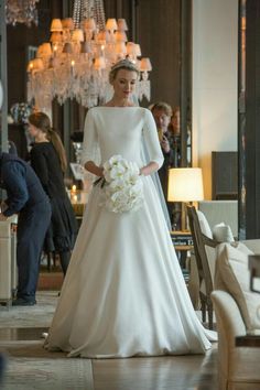 a woman in a white wedding dress standing next to a chandelier