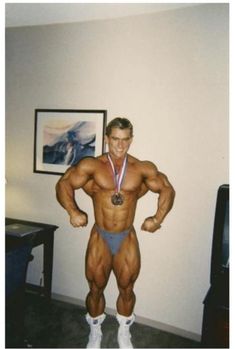 a man posing for a photo with his bodybuilding medal around his neck and chest