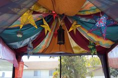 the inside of a tent with decorations hanging from it's ceiling and an open window