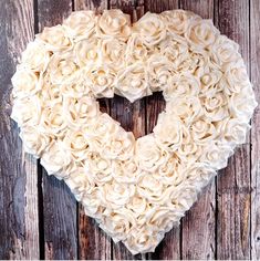 a heart shaped wreath made out of white roses on a wooden background with text overlay