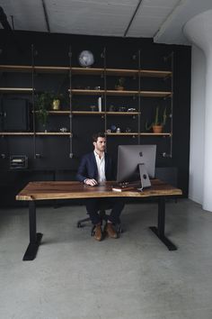 a man sitting at a desk with a laptop in front of him and shelves on the wall behind him