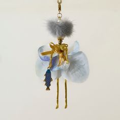 a blue and white flower hanging from a gold plated keychain with an animal charm attached to it