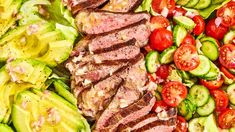 a salad with meat, tomatoes and cucumbers is shown in close up view