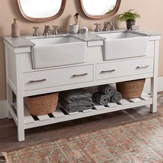 two sinks and mirrors in a bathroom with rugs on the floor next to them