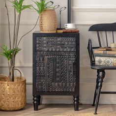 a black cabinet sitting next to a chair and potted plant