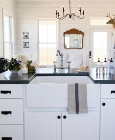 a kitchen with white cabinets and black counter tops is decorated with deer head decorations, candles, and towels