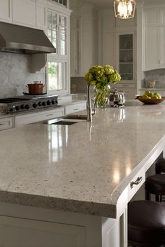 a large kitchen with white cabinets and marble counter tops, along with an island in the middle