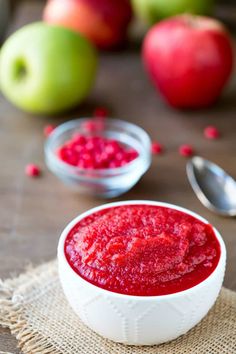 a bowl filled with raspberry sauce next to some apples