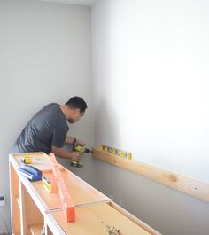 a man is working on the wall in his room with tools and construction materials around him