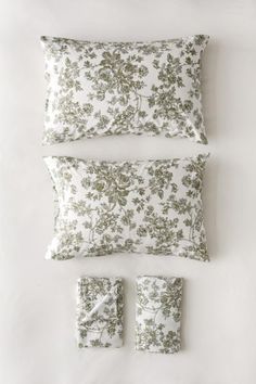 three pillows and two pillow cases on a white surface