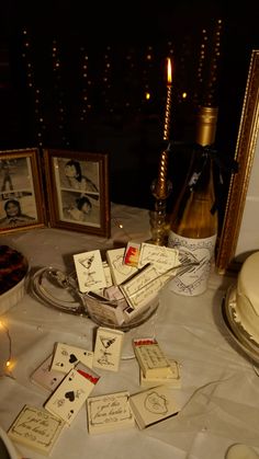 a table topped with lots of cards next to a bottle of wine and two framed pictures