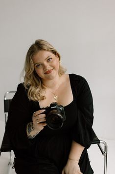 a woman sitting in a chair holding a camera