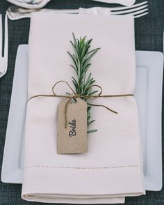 a place setting with napkins, silverware and an empty tag tied to it