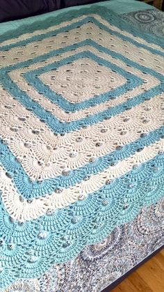 a blue and white crocheted bedspread on top of a wooden floor