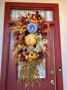 a front door with a wreath and pumpkins on it