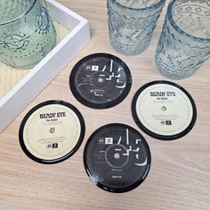 four black and white records sitting on top of a table next to two empty glasses