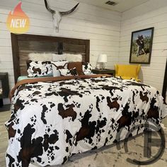 a bed with black and white cow print comforter on top of it in a bedroom