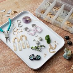 a tray filled with lots of different types of earrings on top of a wooden table