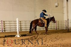 a man riding on the back of a brown horse next to a white pole in an arena