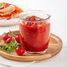 tomato sauce in a glass jar on a wooden tray next to a plate with pizza