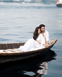 a man and woman are sitting in a boat on the water with their arms around each other