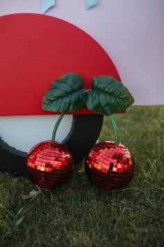 two shiny disco balls sitting next to each other on the grass near a red and white sign