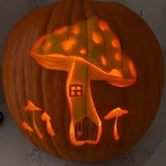 a carved pumpkin with an image of a mushroom on it's face and mushrooms coming out of the top