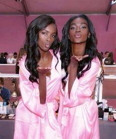 two women in pink robes standing next to each other with their hands on their hips