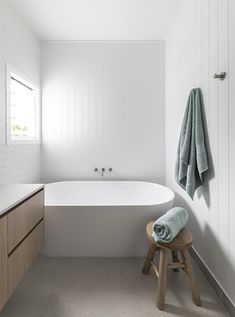 a white bath tub sitting next to a wooden stool