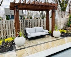 a white couch sitting on top of a patio next to a wooden pergoline