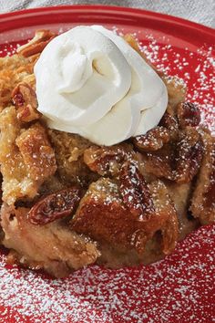 a red plate topped with a piece of pie covered in icing and powdered sugar