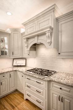 a kitchen with white cabinets and marble counter tops