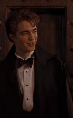 a young man in a tuxedo smiles at the camera