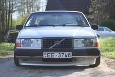 a silver car parked on the side of a dirt road next to grass and trees