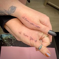 two people holding each other's hands with tattoos on their fingers that say i love you