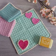 two crocheted hearts are on top of a blanket