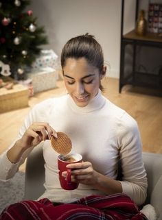 a woman sitting in a chair holding a red cup and a waffle cone on her finger