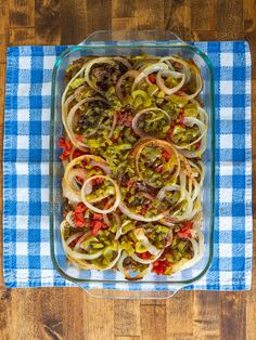 a glass casserole dish filled with pasta and vegetables on a blue checkered cloth