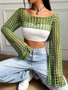 a woman sitting on the floor wearing jeans and a cropped top with openwork