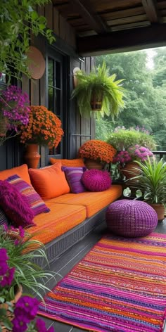 an outdoor living area with orange and purple furniture, potted plants, and colorful rugs