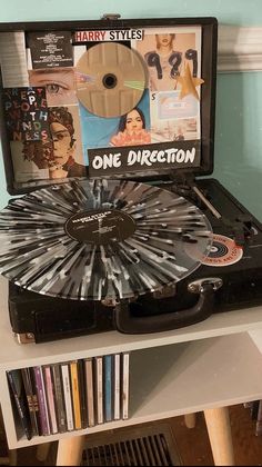 a record player sitting on top of a table next to a dvd case with cds in it