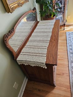 a wooden bench with a crocheted table runner on it