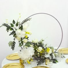 a white table topped with gold plates and flowers