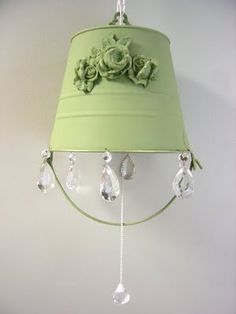 a green lamp hanging from the side of a wall with flowers and leaves on it