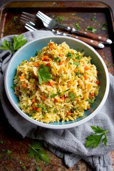 a bowl filled with rice and vegetables on top of a wooden tray next to a fork