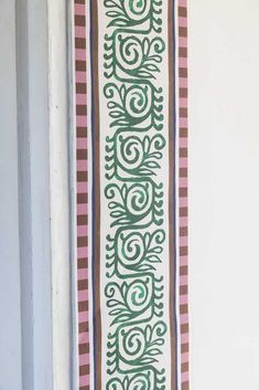 a wall hanging on the side of a building next to a door with an ornamental design